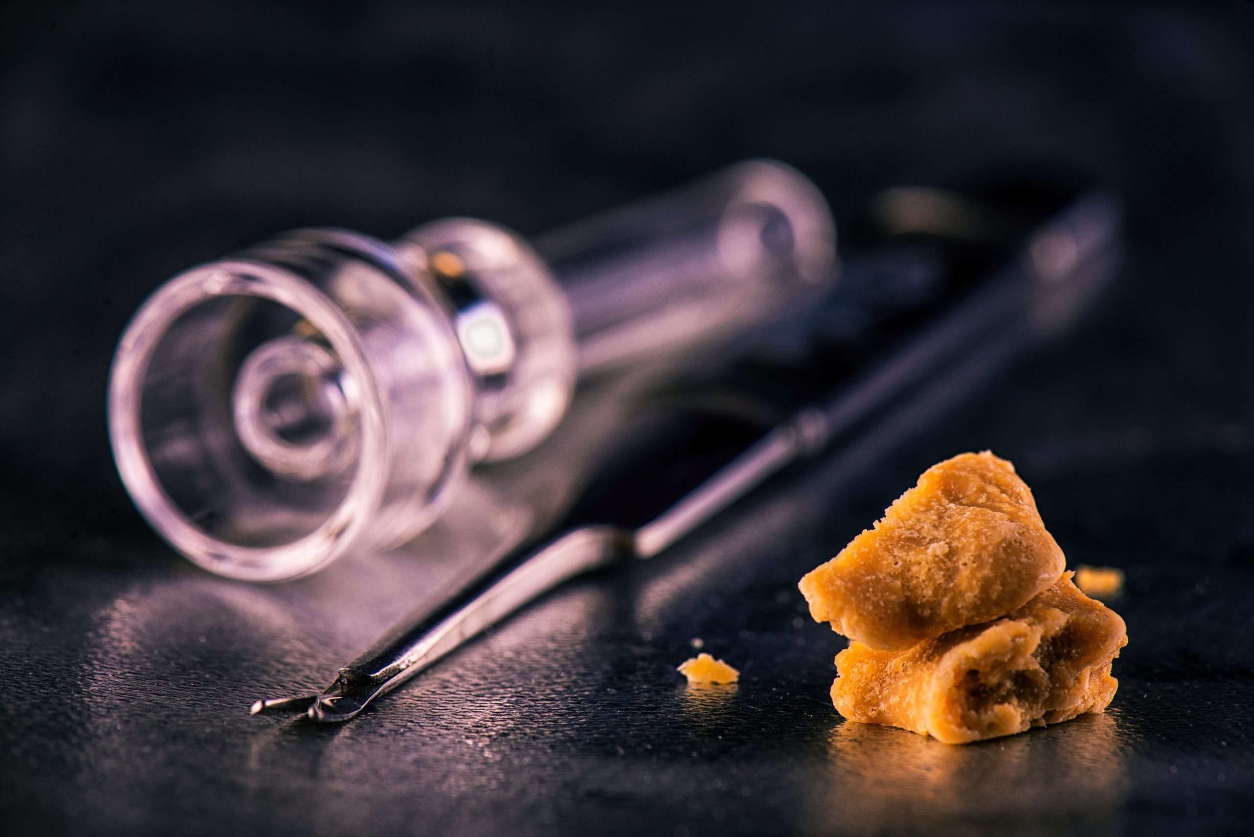 Marijuana extraction concentrate aka wax crumble on dark background with tools